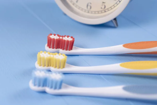 Classic Alarm Clock Three Bright Plastic Toothbrushes Orange Yellow Blue — Stock Photo, Image