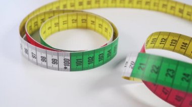 Diyet sırasında vücut parametrelerini ölçmek ve kıyafet dikmek için beyaz bir masanın üzerinde parlak renk santimetresi