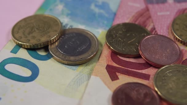 Euro-Banknoten und -Münzen in Großaufnahme auf rosa Hintergrund. Dolly Makro Shot.