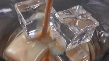 İrlanda kremalı likörü, içinde buz küpleri olan bir bardağa doldurulur. Makro atış. Barda alkollü içecekler..