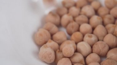 Bezelye tanesi beyaz bir tabağın içine düşer. Makro atış. Yavaş çekim