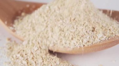 Tahta kahverengi bir kaşığa öğütülmüş buğday tohumu düştü. Beslenme yemeklerinin hazırlanması için organik ürünlerin ve doğal katkı maddelerinin kullanımı