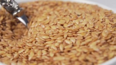 Beyaz bir fincandaki keten tohumları tatlı kaşığıyla karıştırılır. Güzel yavaş çekim ve düşüş. Makro çekim