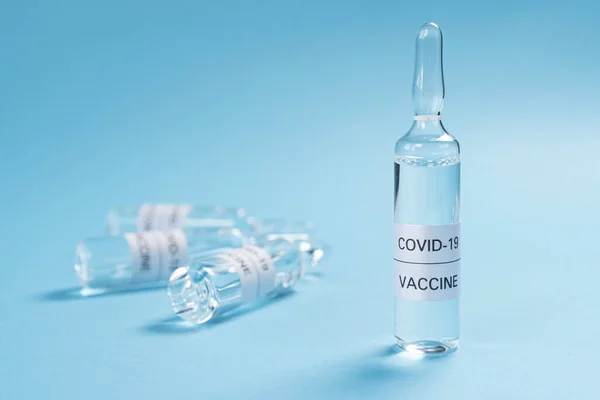 Coronavirus aşısı. Mavi arka planda COVID-19 ilacı olan cam ampuller. Kopyalama. Yakın plan. Yeni bir enjeksiyonun arama ve uygulaması