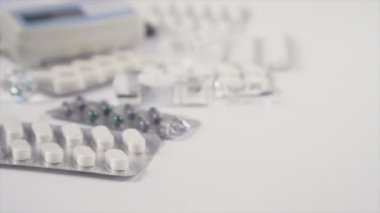 İçinde Coronavirus aşısı olan cam ampul beyaz bir masada tıbbi ekipman ve haplarla birlikte yuvarlanıyor. COVID-19 için ilaç.