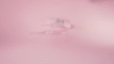 Pembe bir yüzeyde iki cam ampul yuvarlanıyor. Coronavirus aşısı. Yavaş çekim