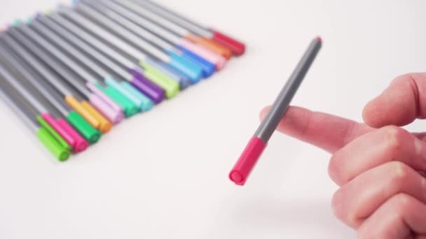 白いテーブルの上に多色のペン 手はバランスで指に1つを保持します 学校用品 — ストック動画