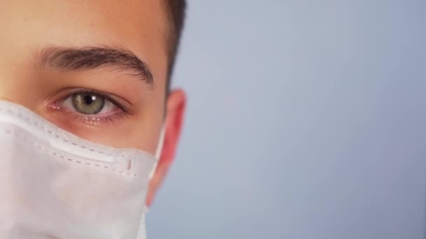 Rostro Joven Con Una Máscara Protectora Médica Sobre Fondo Azul — Vídeo de stock