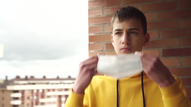 Nastolatek Żółtej Bluzie Ubiera Medyczną Maskę Jednorazowego Użytku Twarzy Balkonie — Wideo stockowe