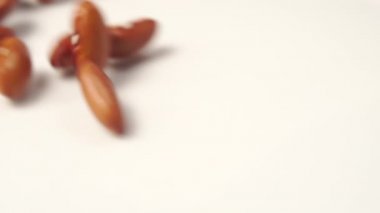 Kırmızı Böbrek Fasulyesi beyaz bir yüzeye döküldü. Kahverengi tohumlar Makro atış. Yavaş çekim