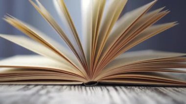 Kütüphanedeki mavi arkaplan üzerine yakın plan kitabı aç. Eski, siyah beyaz bir masada. Sayfalar yavaşça sallanır