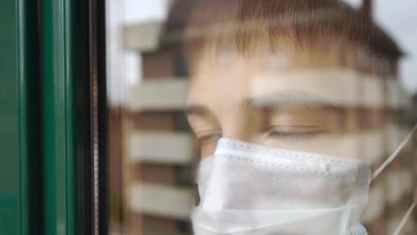 Młody Człowiek Kwarantannie Twarz Maska Medyczna Wygląda Przez Okno Smutnymi — Wideo stockowe