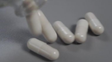 Kapsüller cam bir şişeden gri plastik bir yüzeye dökülüyor. Ağır çekim. Makro atış. Tıbbi konsept. Coronavirus aşısı