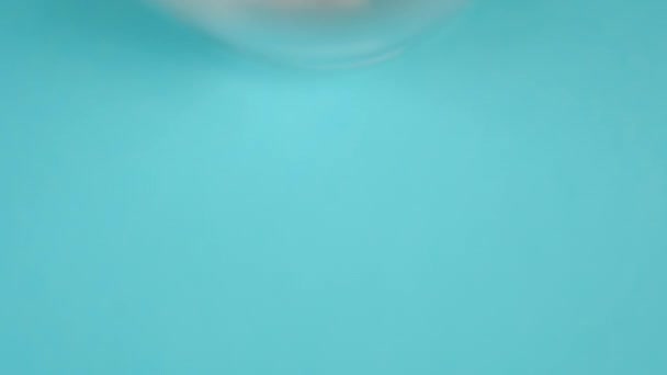 白色药物胶囊特写 在一个蓝色明亮背景的模糊玻璃瓶中 从上面看宏观射击 照相机从上到下缓慢运动 Coronavirus概念 — 图库视频影像