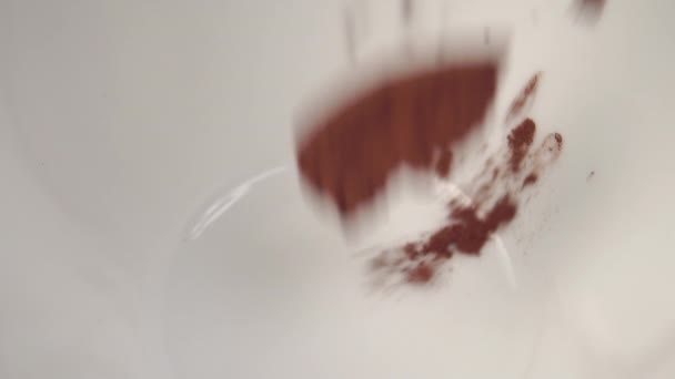 La poudre de cacao instantanée est versée dans une tasse blanche. Faire pure boisson parfumée naturelle. Macro shot. Gros plan. Au ralenti. Petit déjeuner Vitamin Morning concept de boisson 