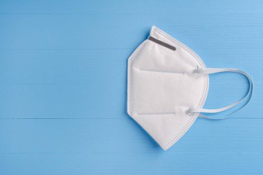 Mavi ahşap arka planda N95 solunum maskesi ve kulaklar için elastik bantlar. - Beyaz. Kopyalama. Yan görüş. Önerilen Koronavirüs Koruması