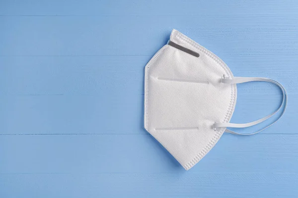 Mavi ahşap arka planda N95 solunum maskesi ve kulaklar için elastik bantlar. - Beyaz. Kopyalama. Yan görüş. Önerilen Koronavirüs Koruması
