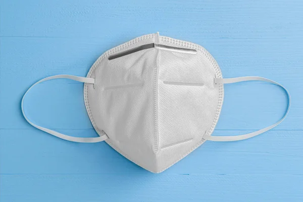 Mavi ahşap arka planda N95 solunum maskesi ve kulaklar için elastik bantlar. - Beyaz. Kopyalama. Yukarıdan bak. Önerilen Koronavirüs Koruması