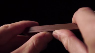 Eller sütlü çikolatayı yakın plan siyah arka plan kırıntılarıyla kırıyor. Ağır çekim. Sağlıksız diyetleri reddetme düşüncesi