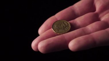 Avucundaki 20 sentlik Avrupa parası siyah arka planda yakın plan çekimde. Parmak parayı hareket ettirir. Ağır çekim. Coronavirüs sonrası mali kriz ve bir şirketin iflası kavramı