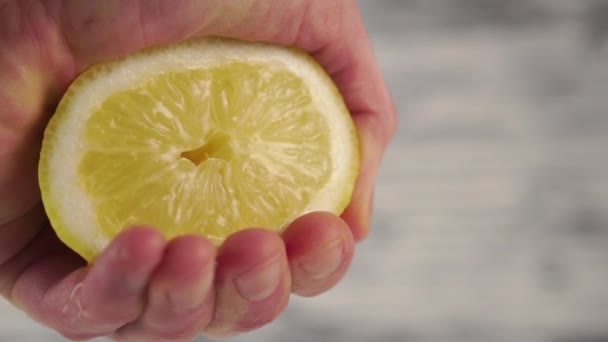 用飞溅挤压柠檬 并将其放到特写处 一个男人的手在木制的背景上 用多汁柑橘类水果做鲜榨果汁 慢动作宏观射门 — 图库视频影像