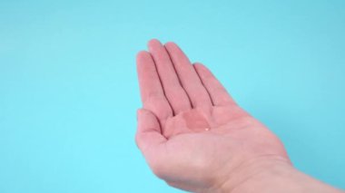 Mavi arka planda alkollü el dezenfektanı kullanıyor. Plastik bir cep şişesinde. Koronavirüs enfeksiyonunun önlenmesi. Tıbbi antiviral konsept