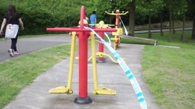 Oviedo, İspanya - 21 Mayıs 2020. Spor sahası, kırmızı sarı spor ekipmanlarıyla çevrili bir parkta mavi tehlike bandıyla çevrili. Karantinada. Apartman sakinleri acil durum önlemleri sonrasında yürüyüşe çıktı