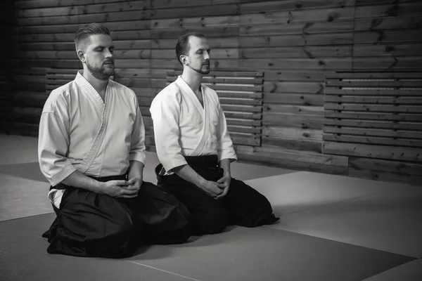 Dos hombres en kimono se sientan en seiza y practican meditación en un dojo — Foto de Stock