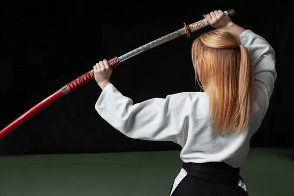 Hermosa chica sosteniendo una espada katana japonesa en sus manos por encima de su cabeza — Foto de Stock