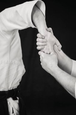 Aikido tekniğinden acı dolu bir el tekniği uygulayan genç bir adamın yakın çekimi.
