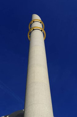Parlak mavi gökyüzünün önündeki iki altın yüzüklü kolonya camisinin minaresi.