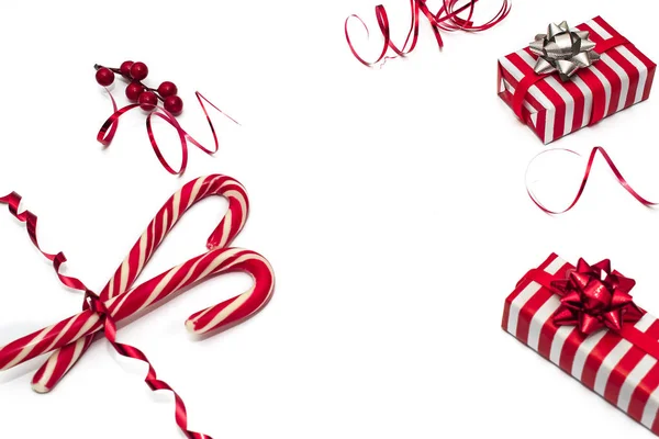 クリスマスの装飾赤いリボンで飾られた赤い果実とコーンの枝を持つクリスマスカード 赤と白のストライプの紙のギフトボックス クリスマスキャンディ平面配置とコピースペース — ストック写真
