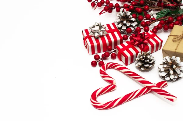 Noel dekoru. Kırmızı böğürtlen ve koni dallı bir Noel kartı, kırmızı kurdeleyle süslenmiş. Kırmızı ve beyaz çizgili hediye kutuları. Noel şekeri. Düz yat ve boşluğu kopyala.