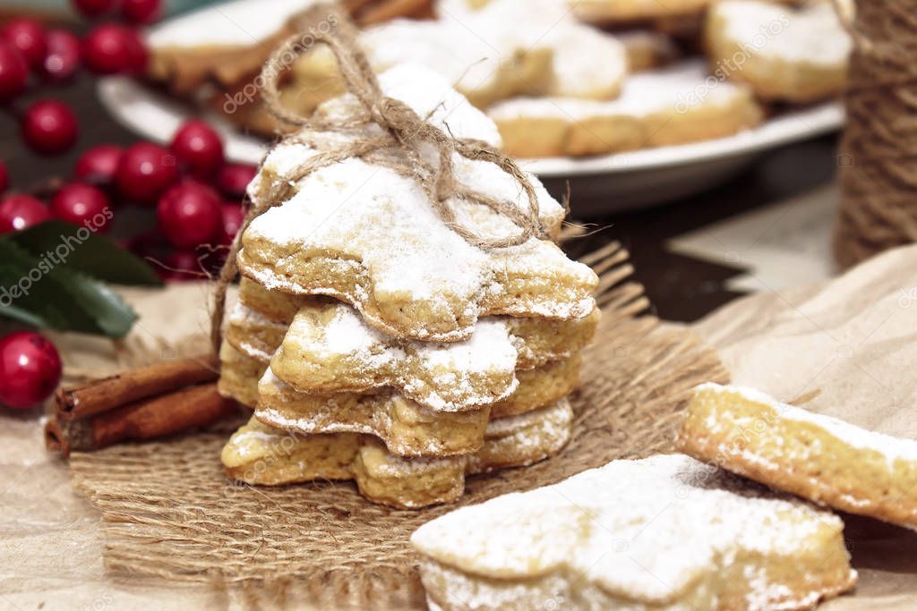 Homemade egg-free vegetarian cookies sprinkled with powdered sugar. Festive cookies on crumpled paper in the shape of a Christmas tree, a heart, a butterfly and a bird.