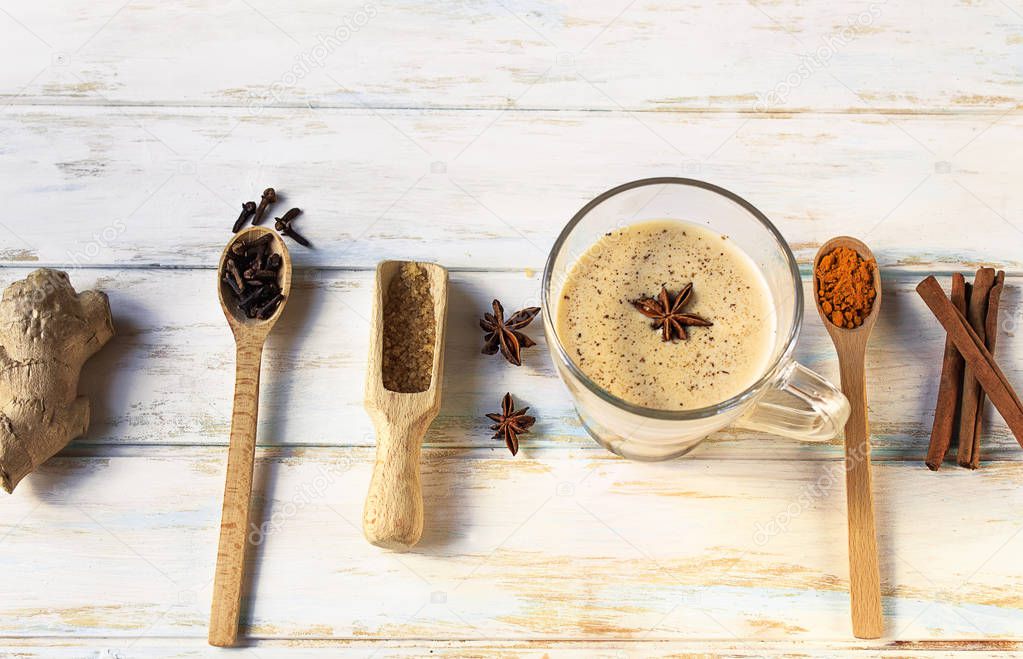 Ingredients for healthy indian masala chai or tea with diferent spices (cardamon, anice, cinnamon, ginger) on a white wooden background