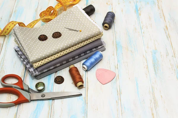 Sewing tools and fabric on a white background. Concept for needlework, stiching, embroidery and tiolori. Sewing multicolored threads, needles, ngpins, fabric, buttons and sewing centimeter. Top view, flatlay whith copy space.