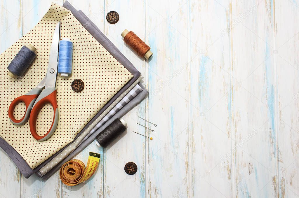 Sewing tools and fabric on a white background. Concept for needlework, stiching, embroidery and tiolori. Sewing multicolored threads, needles, ngpins, fabric, buttons and sewing centimeter. Top view, flatlay whith copy space.