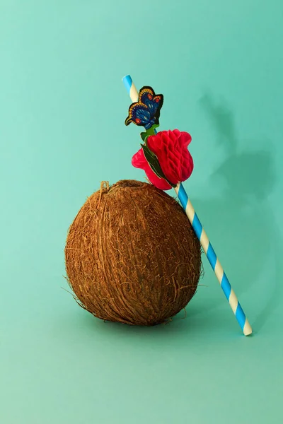 Coconut and cocktail straw on a blue background. The concept of summer cocktails and summer holidays