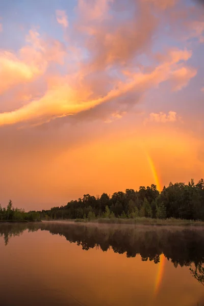 Pemandangan musim panas, pelangi dalam cahaya matahari terbenam di atas danau Stok Foto