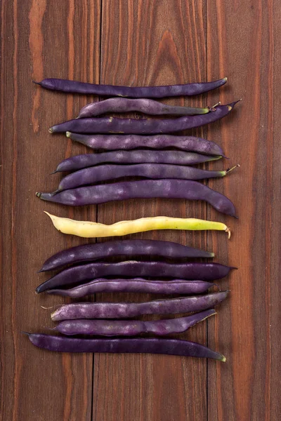 purple string beans on a wooden background