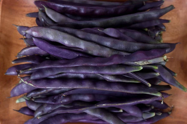 Purple string beans on a wooden background — Stock Photo, Image