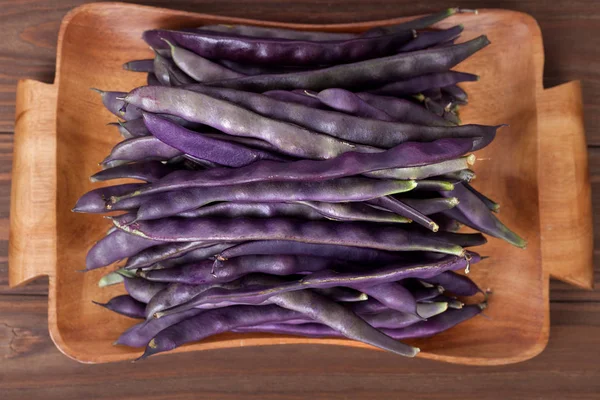 purple string beans on a wooden background