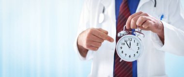 bir çalar saat tutan erkek doktor 
