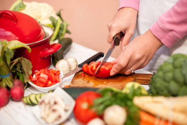 Huisvrouw snijden tomaat met een mes — Stockfoto