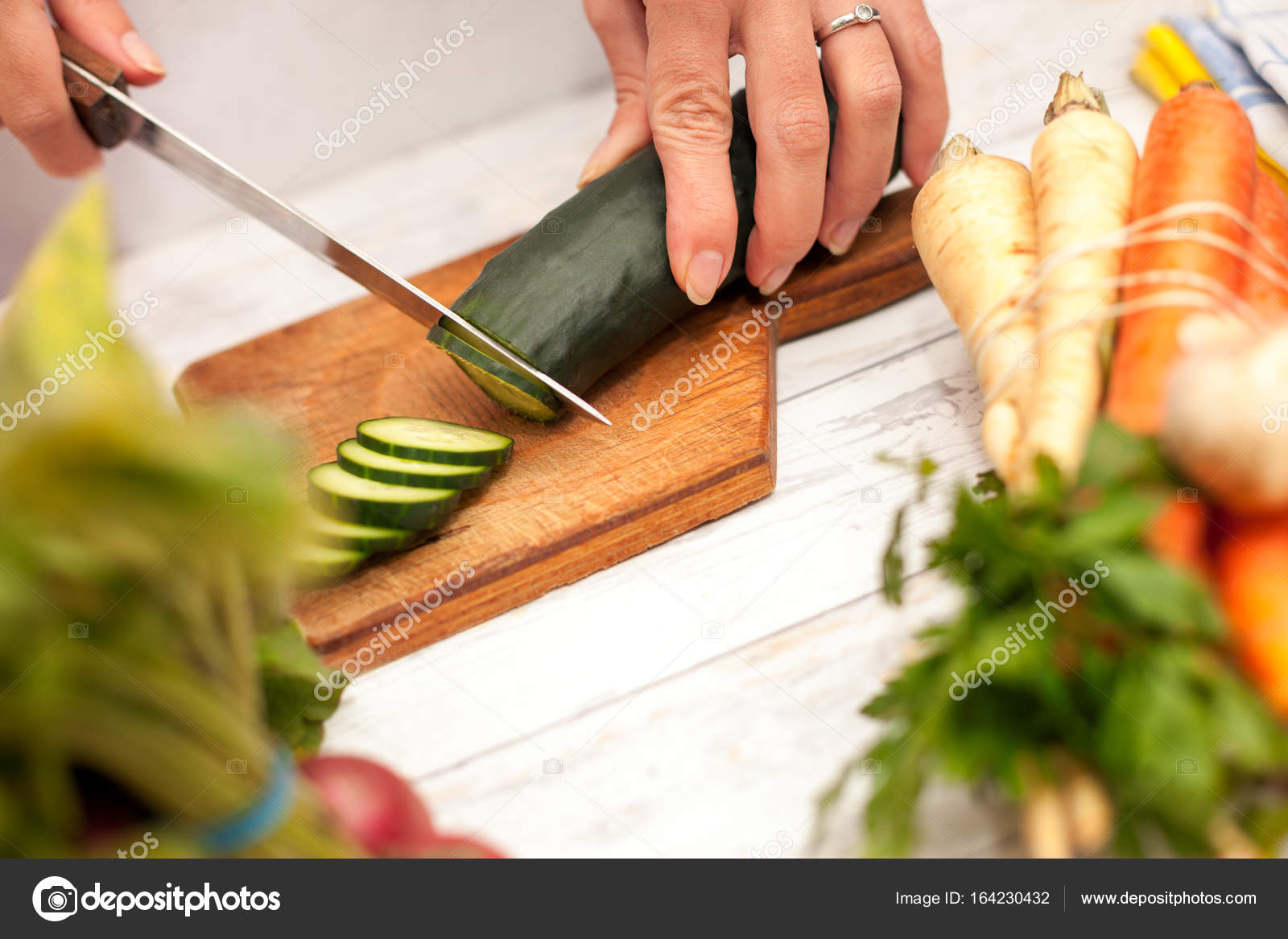 Woman cutting cucumber with a knife in the kitchen — Stock Photo