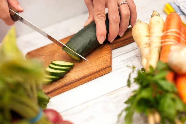 Frau schneidet Gurke mit Messer in der Küche — Stockfoto