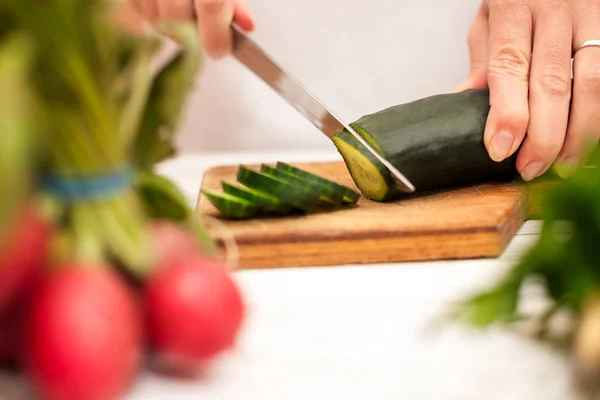 Hausfrau schneidet Gurke in der Küche — Stockfoto