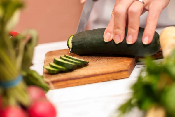 Hausfrau schneidet Gurke mit Messer in der Küche — Stockfoto