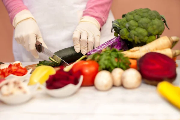 Mujer con guante blanco rebanando pepino y preparando vegetales — Foto de Stock