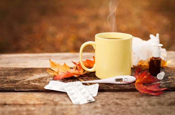 Pohár s horkým čajem a teploměr ukazuje vysokou teplotu po — Stock fotografie